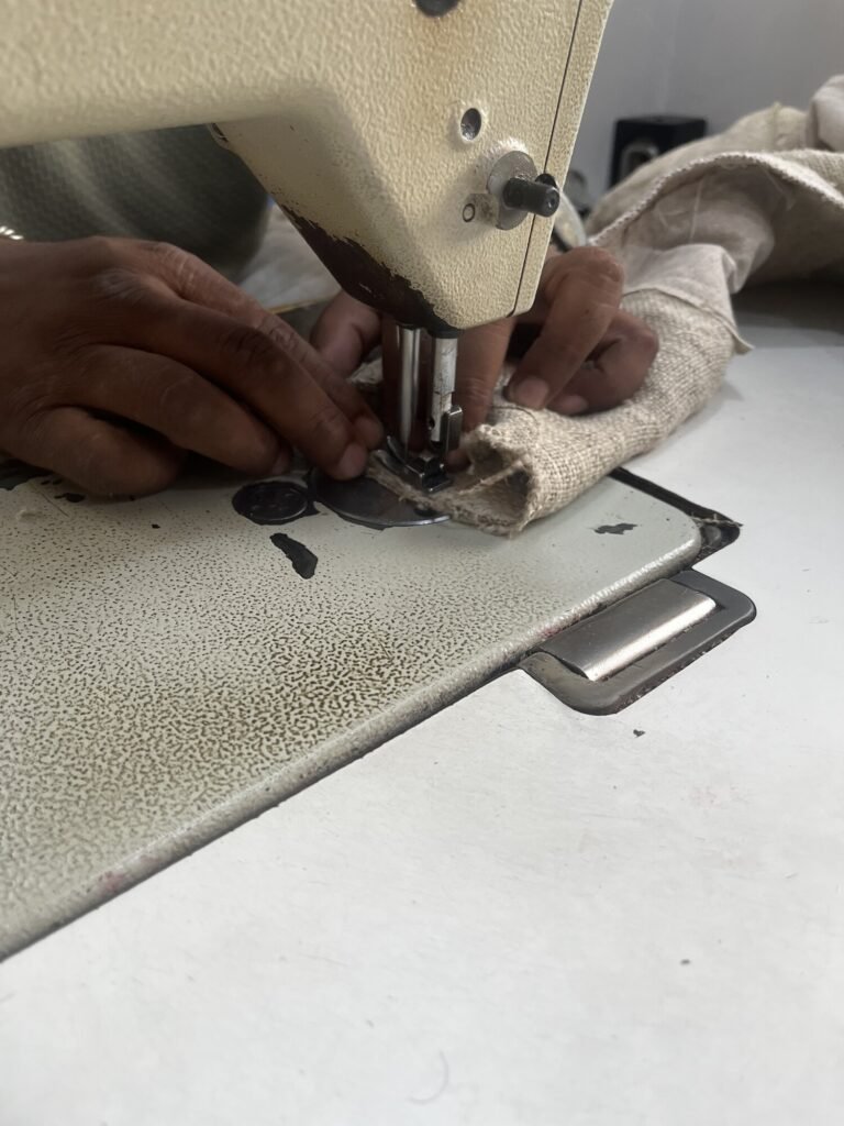 Tailor machine-stitching a new, longer hemp cuff onto a chore jacket sleeve