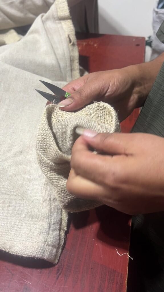 Tailor unpicking a stitched seam on a handwoven hemp chore jacket with small scissors
