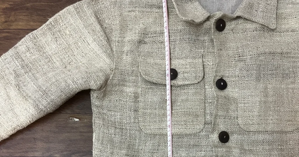 Handwoven hemp chore jacket sample laid flat, with a tape measure running down the front