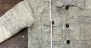 Handwoven hemp chore jacket sample laid flat, with a tape measure running down the front