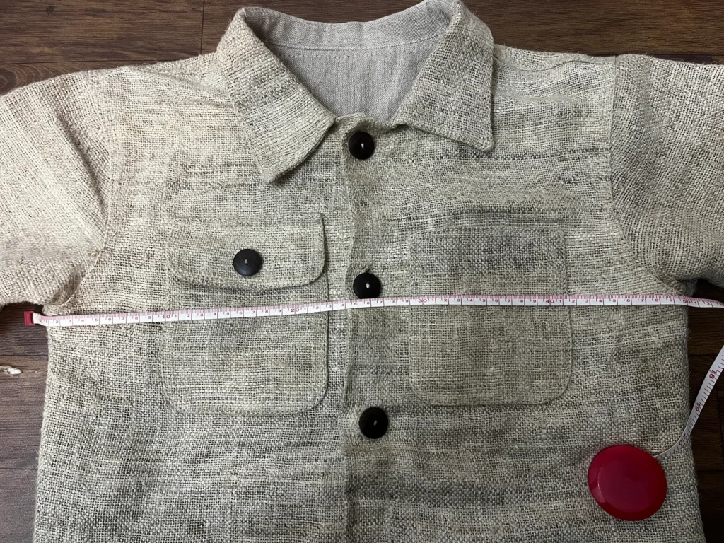 Tape measured pit to pit across a handwoven hemp chore jacket laid on its side