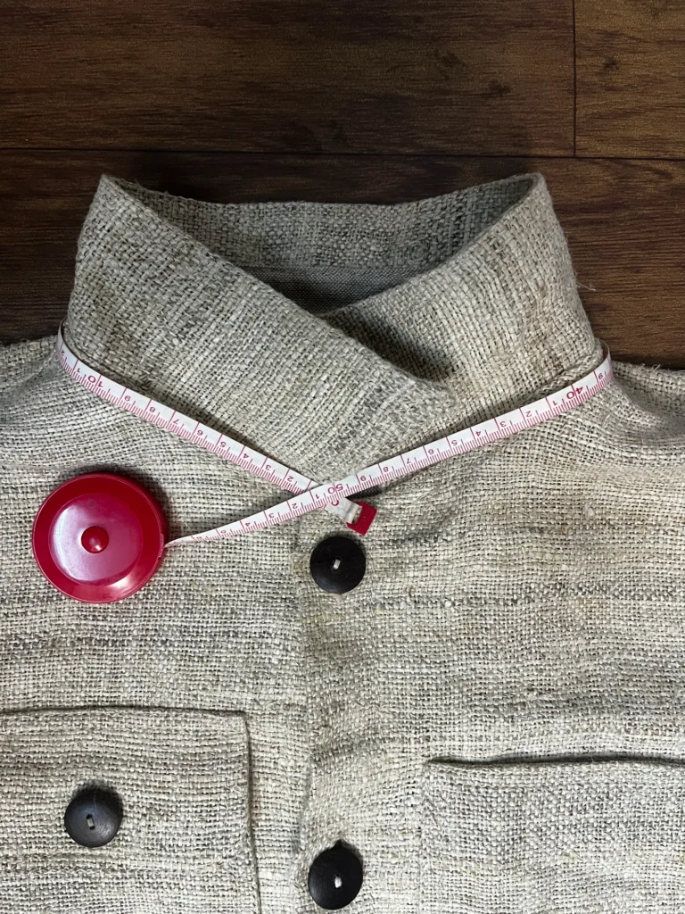 Tape run point to point along the neck seam of a handwoven hemp jacket collar