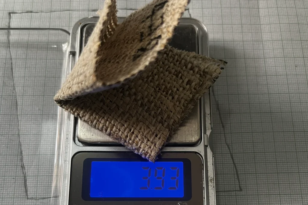 Second handwoven hemp swatch, folded to fit, on a 0.01 g digital pocket scale reading 3.93 g